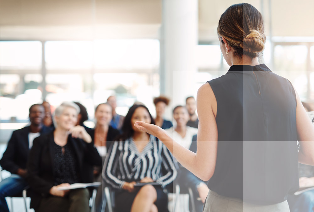 A woman speaking to a crowd about the benefits of Datasite's virtual data room